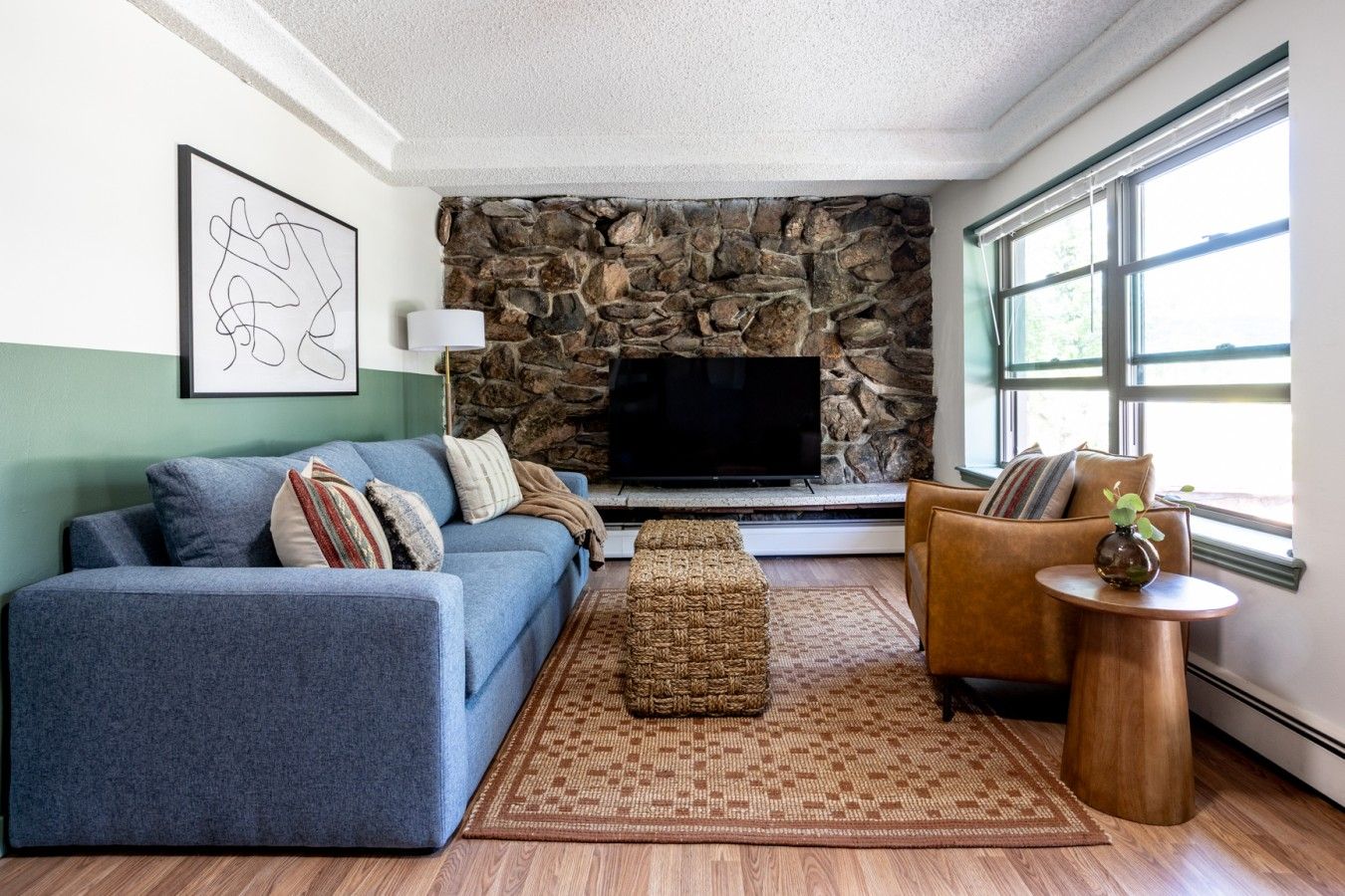 Living room with sage green lower walls and stone fireplace
