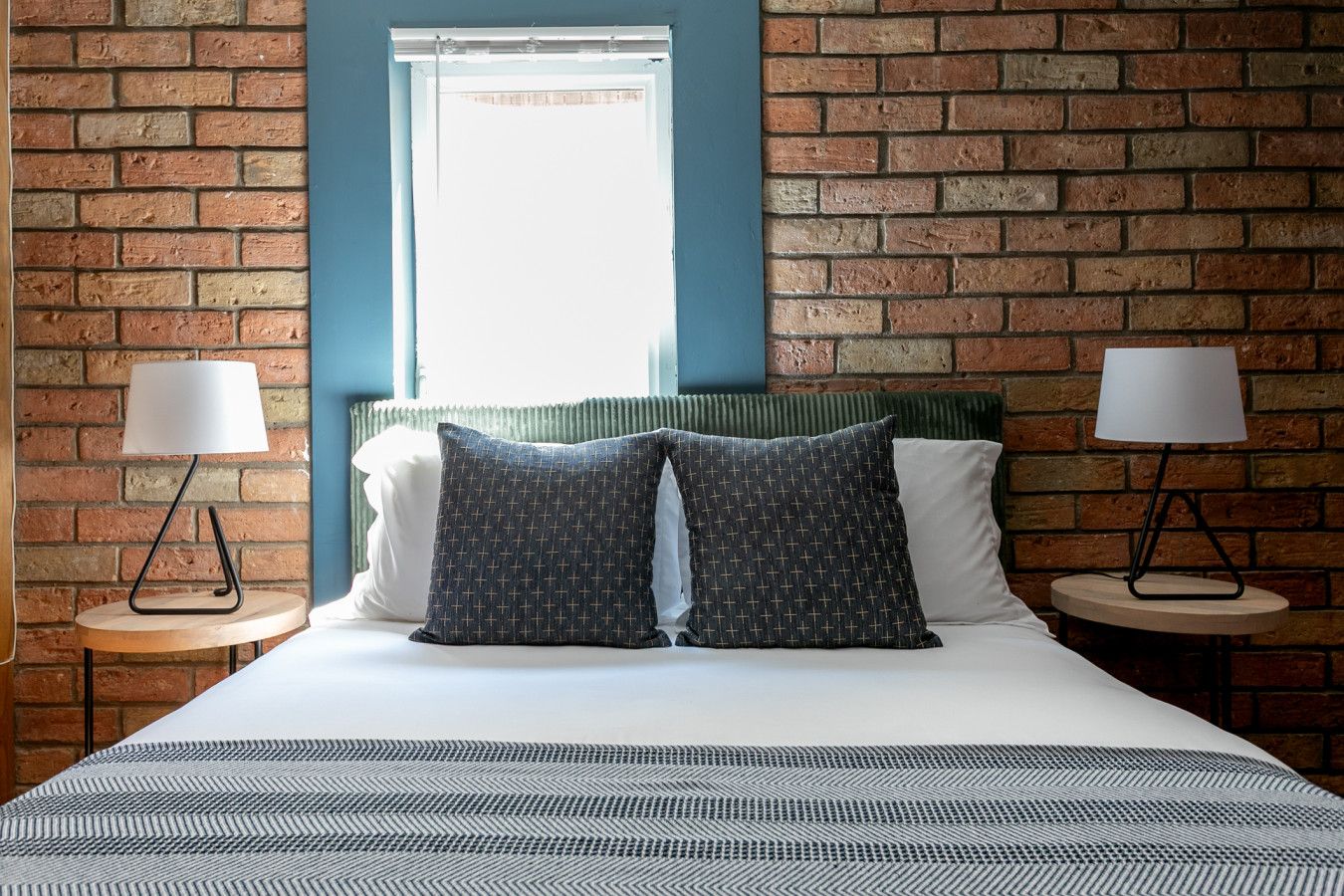 Bedroom with sky blue accent beside red brick wall